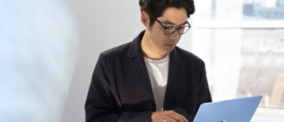 A man wearing glasses looking at a laptop.
