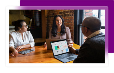 A group of people sitting at a table with a laptop on it
