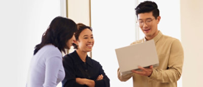 A group of people standing around a laptop.