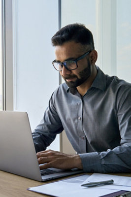 A person wearing glasses and using a laptop.