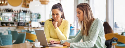 Two women are working on laptop.