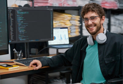 Smiling developer at desk with code screens