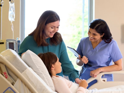 A nurse assists a patient in a hospital bed.