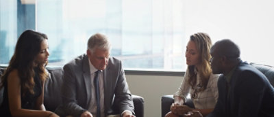 A group of people gathered in a room sitting around round table