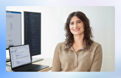 A person sitting in front of a computer with a laptop on a table.