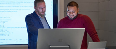 A couple of men looking at a laptop.