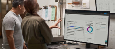 Two people review a security dashboard on a large monitor.
