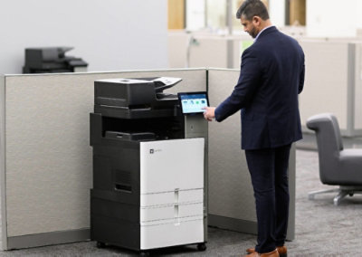 Person using a touchscreen printer in an office cubicle to select print options.