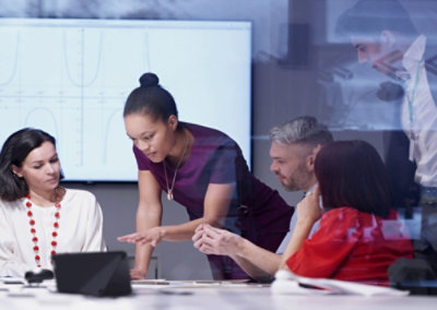 Team members gathered around a laptop discussing work during a meeting.