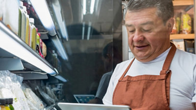 A man wearing apron holding a tab.