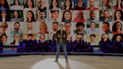 A man standing at a podium, in the background multiple pictures are displayed on the screen.