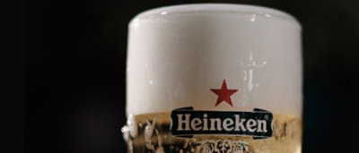 A close-up of a glass of beer with Heineken text visible.