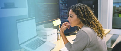 A woman sitting at a desk looking at a computer screen.