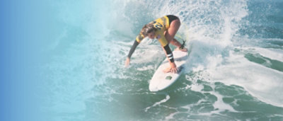 A woman surfing on a wave under a blue sky with clouds.