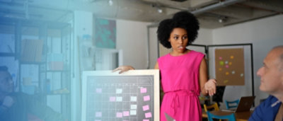 A woman in a pink dress holding a board with colorful dots.