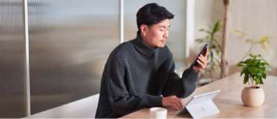 A man looking into mobile and have a tea.