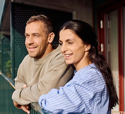A smilimg couple standing, appear relaxed and happy, looking off into the distance.