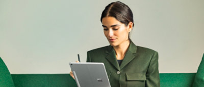 A person wearing a green suit in front of a green and white background.
