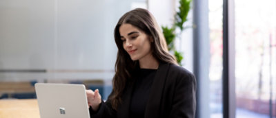 Person in a black blazer working on a laptop in a modern office setting.