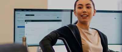 Woman presenting in office with screens behind her.