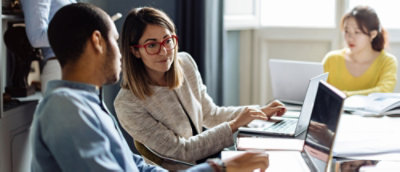 Team collaborating around laptops at a meeting table