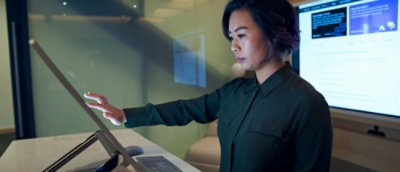 Person using a touch‑enabled vertical display with digital content in a modern workspace.