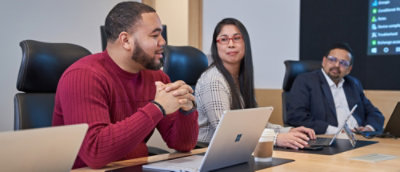 Team seated at a conference table using laptops during a meeting.