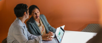 A man and woman discussing while looking at the laptop screen