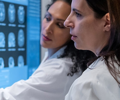 Two clinicians reviewing medical scan images together on a large digital display.
