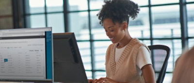 Person working at a desktop workstation with multiple monitors displaying an application interface.