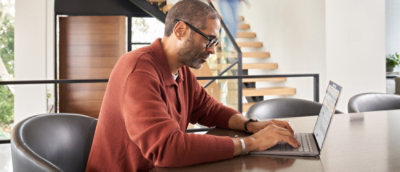 A man in aPerson working on a laptop at a table in a modern office space with a staircase in the background.a suit standing in front of a computer screen.