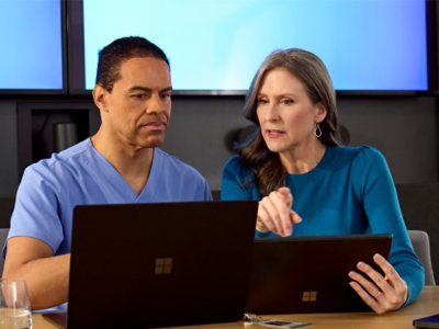 A doctor and women holding a tab and laptop watching together
