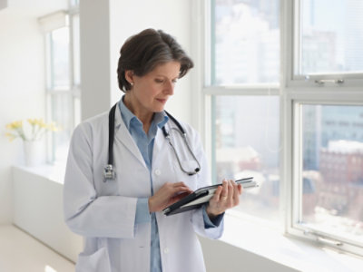 A Doctor holding a tab and looking into it.