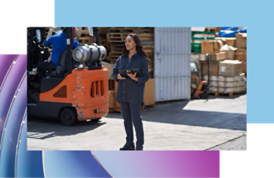 A woman standing in front of a forklift near a white metal fence.