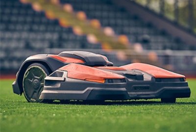 A robot lawn mower navigating through lush green grass in a stadium.