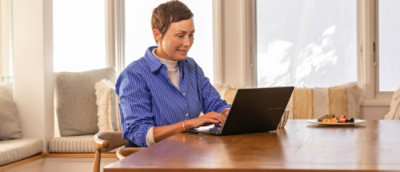 A person sitting at a table using a laptop.