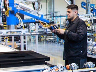 A man holding a device in a factory setting.