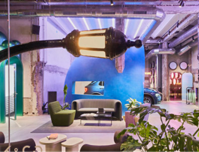 A modern indoor space with a unique, curved streetlamp fixture, contemporary furniture, plants, and a blue wall