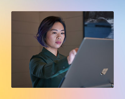 Une personne aux cheveux courts se concentre sur un écran devant elle. Elle est à l’intérieur et porte un haut vert foncé.