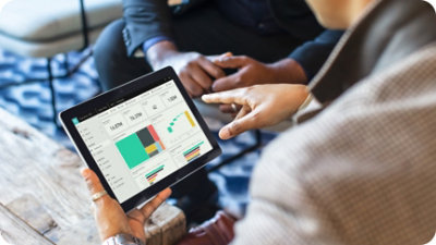 Deux personnes discutent des visualisations de données affichées sur un écran de tablette.