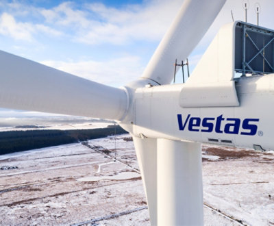 Detail větrné turbíny Vestas se zasněženou krajinou v pozadí.