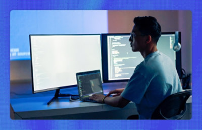 A man sitting at a desk with two monitors