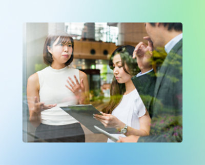 Trois personnes lors d'une réunion d'affaires. Une femme parle tandis que l'autre femme se concentre sur un clipboard. 