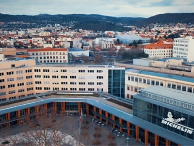 A building with many windows and a Michelin logo, surrounded by snow-covered ground and trees.