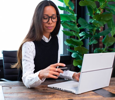 Person working at a desk using a laptop in a quiet workspace with indoor plants nearby.
