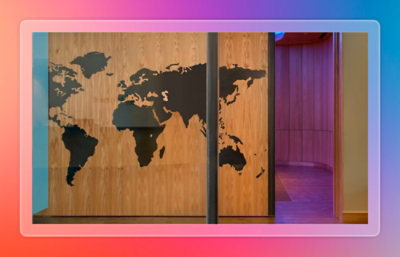 World map artwork mounted on a wooden wall inside a modern office hallway with soft ambient lighting.