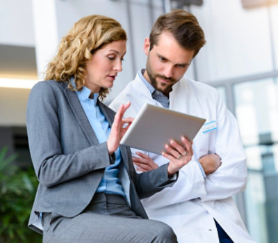 Healthcare professionals reviewing information together on a tablet in a clinical environment.