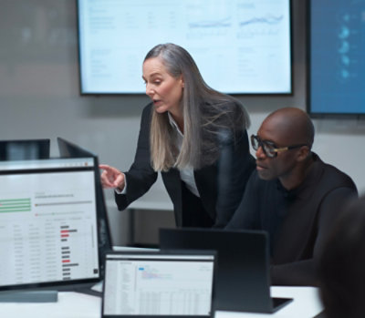 Team collaborating at a workstation while reviewing data dashboards displayed on multiple monitors.
