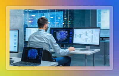 A man sitting at a desk with multiple computers.