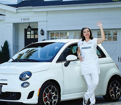 Progressive Agent standing next to a car waving